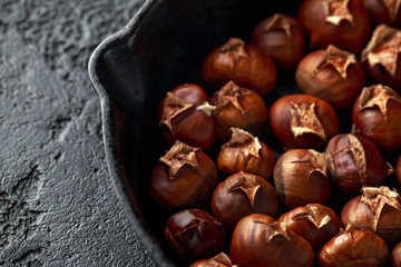 Roasted chestnuts served in cast iron vintage pan.