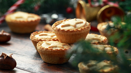 British Christmas mince pies with decoration, gifts, green tree branch on wooden rustic table