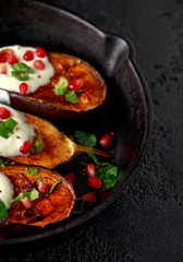 Grilled eggplants with yogurt sauce, pomegranate seeds, parsley and green onion in cast iron vintage pan.