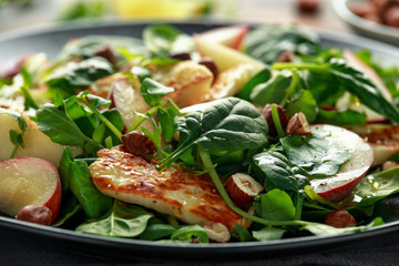 Grilled Halloumi Cheese salad with peach fruit, nuts and spinach, arugula mix. healthy food. closeup