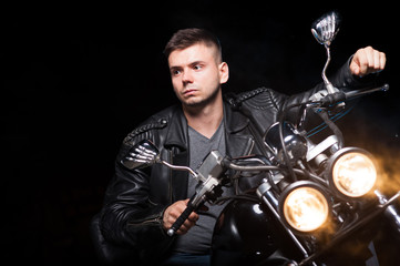 Fototapeta na wymiar Cute biker in leather jacket sits on a motorcycle 