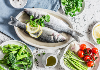Healthy balanced ingredients for lunch - sea bass, asparagus, tomatoes, broccoli, green peas, olive oil and spices. On a light background, top view. Flat lay
