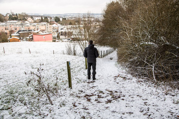 man walking carefully down the hill in the snow on an unmarked path
