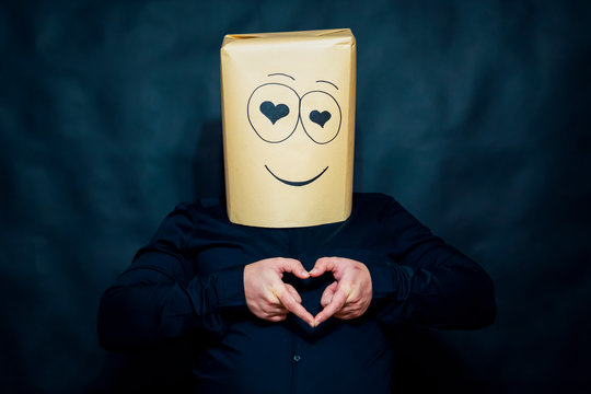 The concept of emotions. A man with his fingers depicts a shape in the shape of a heart. Looks lovers eyes. On the face smile and happiness.