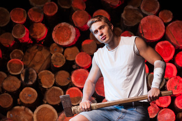 Fototapeta premium Close-up of a lumberjack worker with an ax in his hands against the background of firewood 