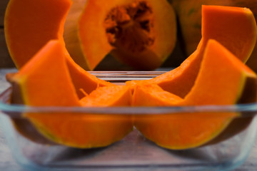 Slices of ripe pumpkin in a glass bowl. Orange pulp. Raw vegetables. Light background.