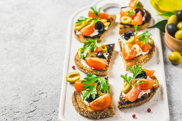 Olives cherry tomatoes goat cheese bruschetta. Selective focus, space for text.