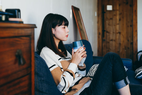 Woman sitting on sofa with cup of tea