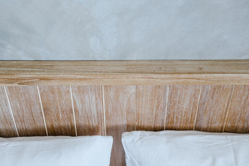 Light wooden bedhead, grey concrete wall, white bed sheets. Minimal loft design, flat interior details