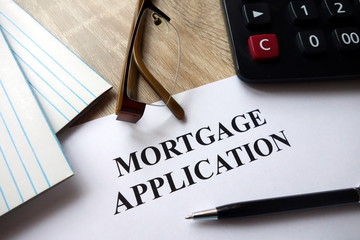 Mortgage application document with pen, calculator and   glasses on desk