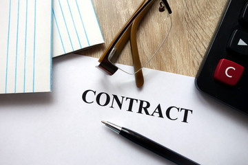 Contract document with pen, calculator and glasses   on desk