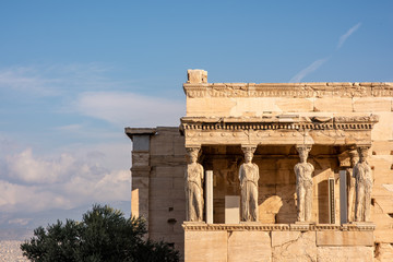 Obraz premium The ancient Erechtheion temple with the beautiful Caryatid pillars on the porch, on the Acropolis in Athens, Greece.