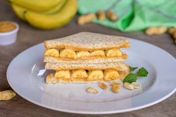 Sandwich with peanut butter and banana on plate.