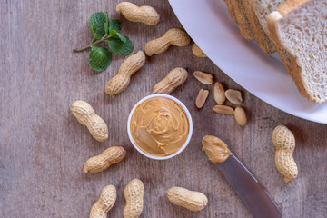 Fototapeta premium Creamy peanut butter with nut and bread on wood table.