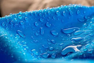 Water drops on waterproof blue nylon fabric. Macro detail view of woven synthetic waterproof...