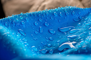Water drops on waterproof blue nylon fabric. Macro detail view of woven synthetic waterproof...