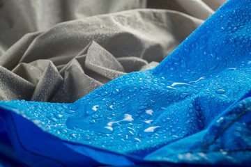 Water drops on waterproof blue nylon fabric. Macro detail view of woven synthetic waterproof clothing. Waterproof fabric with waterdrops. Rain Drops on Water Resistant Textile Coating.