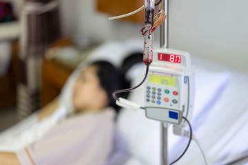 Close up IV set, add blood and blurry of patient illness sleeping on hospital bed. Medical...