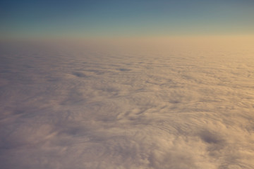 Fototapeta na wymiar Layer of clouds taken from aircraft above scene illuminated by low evening or morning sun rays of warm golden color. Easy background photography of simple composition and empty space.