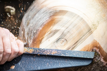 detail macro of wood turning with flying sawdust shavings while making a bowl