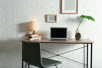 Stylish workplace with laptop on table in home office. Space for design