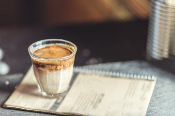 Hot latte coffee in glass on wooden table at coffee shop.