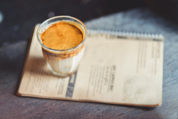 Hot latte coffee in glass on wooden table at coffee shop.