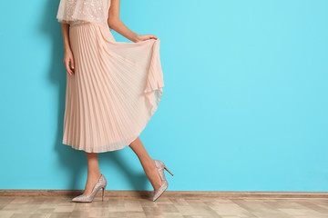 Young woman with beautiful long legs in stylish outfit near color wall, closeup. Space for text