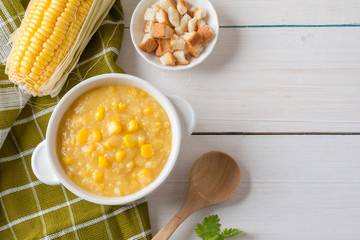 Corn soup in white bowl and crispy bread with corn on white table. Top view with Copy space.