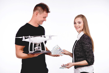 Boy and girl are holding flying drones and money, smiling. On a white background