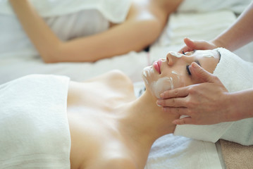 Beautiful caucasian woman cleaning makeup before massage and making facial mask treatment on face in Spa salon.