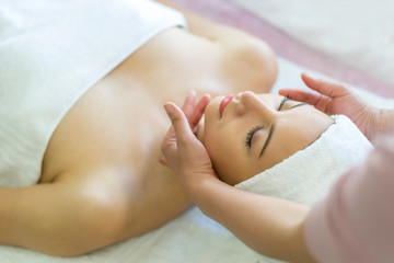 Fototapeta na wymiar Beautiful caucasian woman relaxation and lying with massage on face in spa salon.