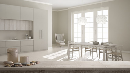 Wooden vintage table top or shelf with candles and pebbles, zen mood, over blurred classic white kitchen with wooden and beige details, dining table laid for two, modern interior design