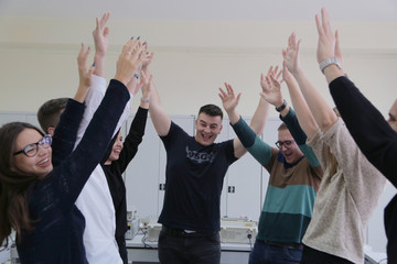 Group of young students in technical vocational training celebrating finishing project with holding...