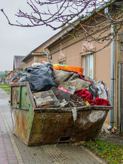 a large metal waste container on the citys street, full of waste