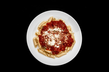 penne meal with red sauce and grated cheese, black background, top view