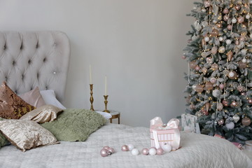 Elegant Christmas tree with white and pink toys in the bedroom of luxury apartments