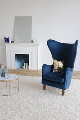 fireplace and blue velvet armchair in a room with white walls in luxury apartments