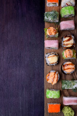 Assortment of baked and fresh sushi rolls on a wooden board. Japanese cuisine