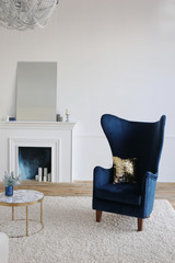 fireplace and blue velvet armchair in a room with white walls in luxury apartments