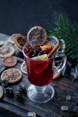 Homemade mulled wine with oranges, apples, cinnamon, cranberries and fir tree on rustic wooden background