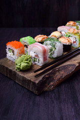 Assortment of baked and fresh sushi rolls on a wooden board. Japanese cuisine