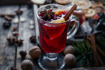 Homemade mulled wine with oranges, apples, cinnamon, cranberries and fir tree on rustic wooden background