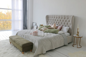 Fototapeta na wymiar elegant bed with green and gild pillows at bedroom of the luxury apartment with white walls