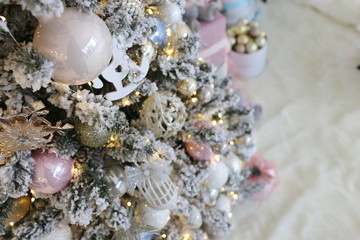 elegant beautiful new year and Cristmas tree with white, pink and blue toys under the instant snow 