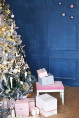 christmas tree and gift boxes in the room with dark blue walls