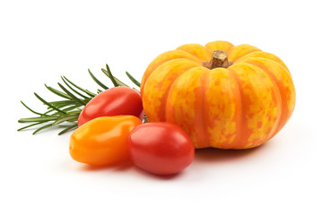 Mini orange decorative pumpkin with cherry tomatoes, isolated on a white background. Close-up