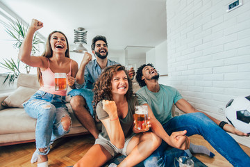 Happy friends or football fans watching soccer on tv and celebrating victory at home.Friendship,...