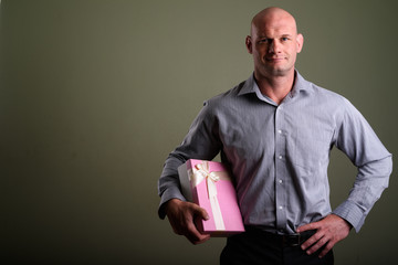 Portrait of bald muscular businessman against colored background