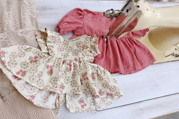 old vintage beige sewing machine and red little dress for girl and doll in atelier with white brick...